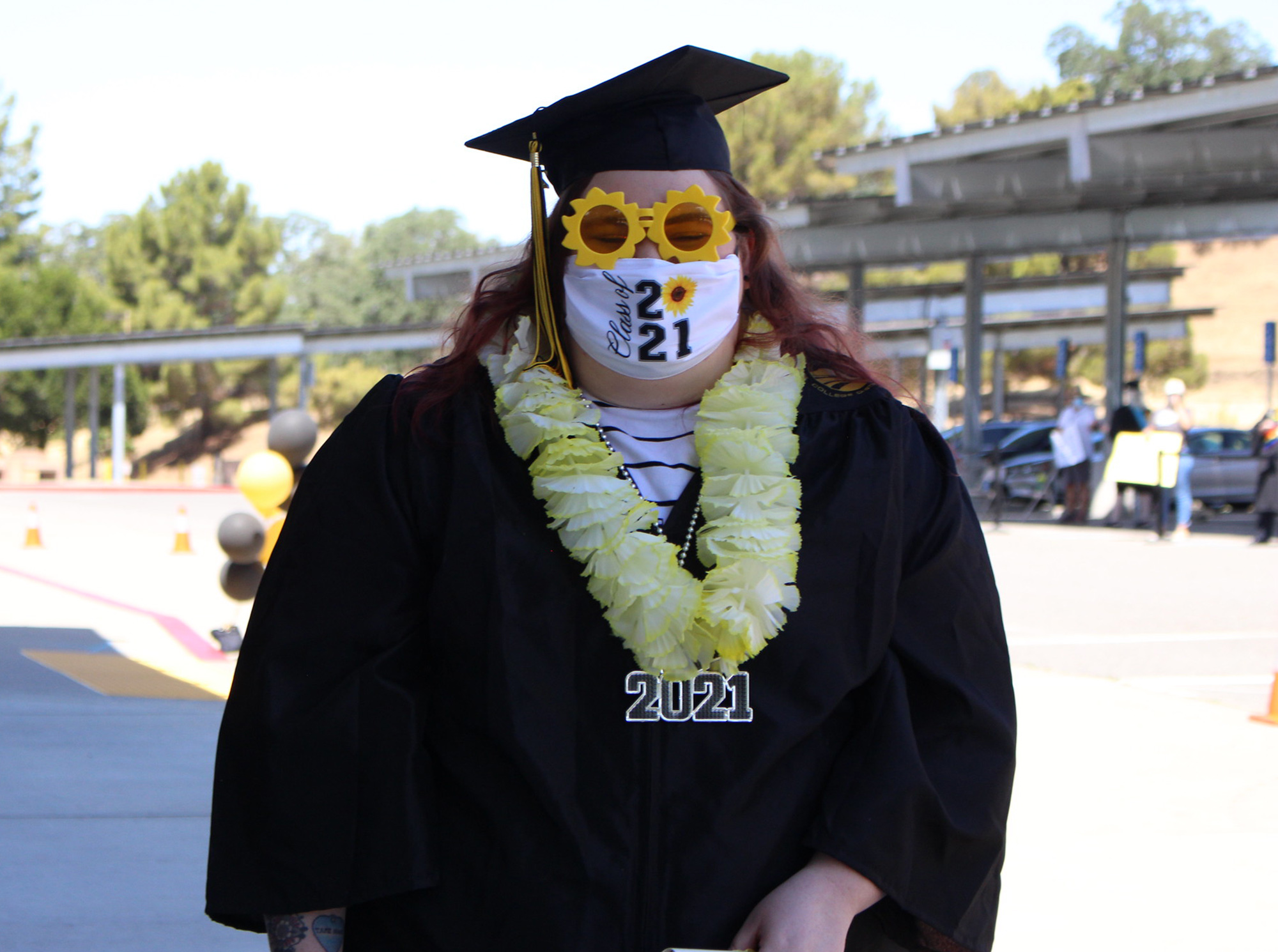 A graduate wears a face mask and lanyard that reads class of 2021.