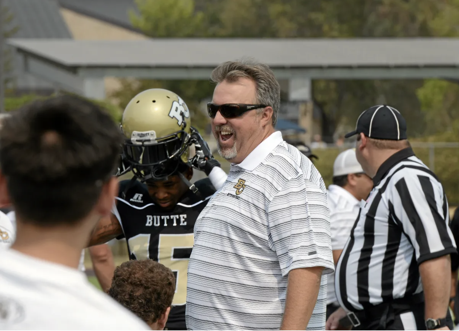 Coach Jeff Jordan smilles while giving football players a pep talk. 
